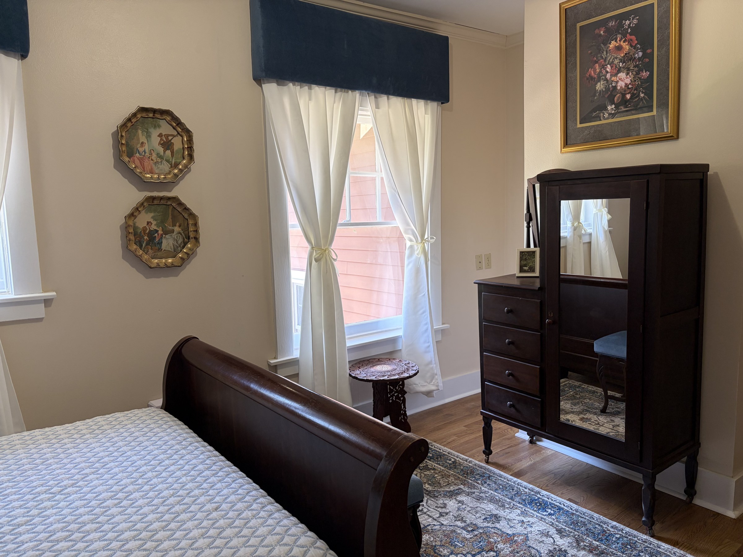 The Lightle Room: a dark wood sleigh bed with a quilted cream coverlet, navy valance, and mirrored armoire.