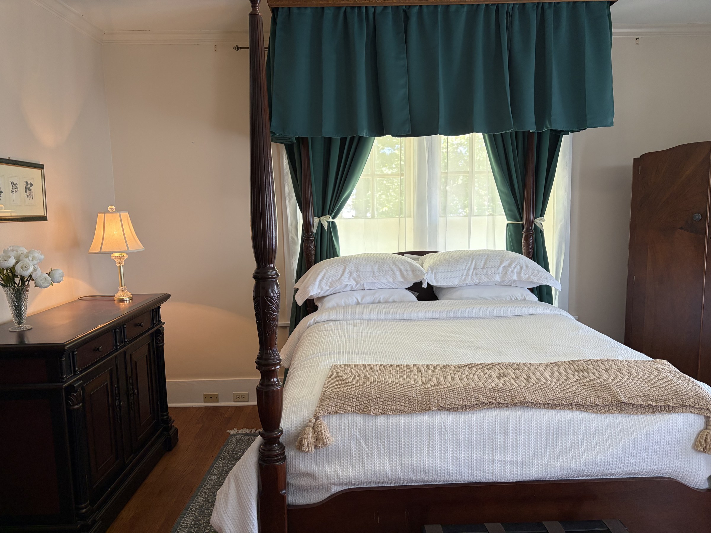 Mary: a dark wood four-poster bed with white linens and forest-green curtains.