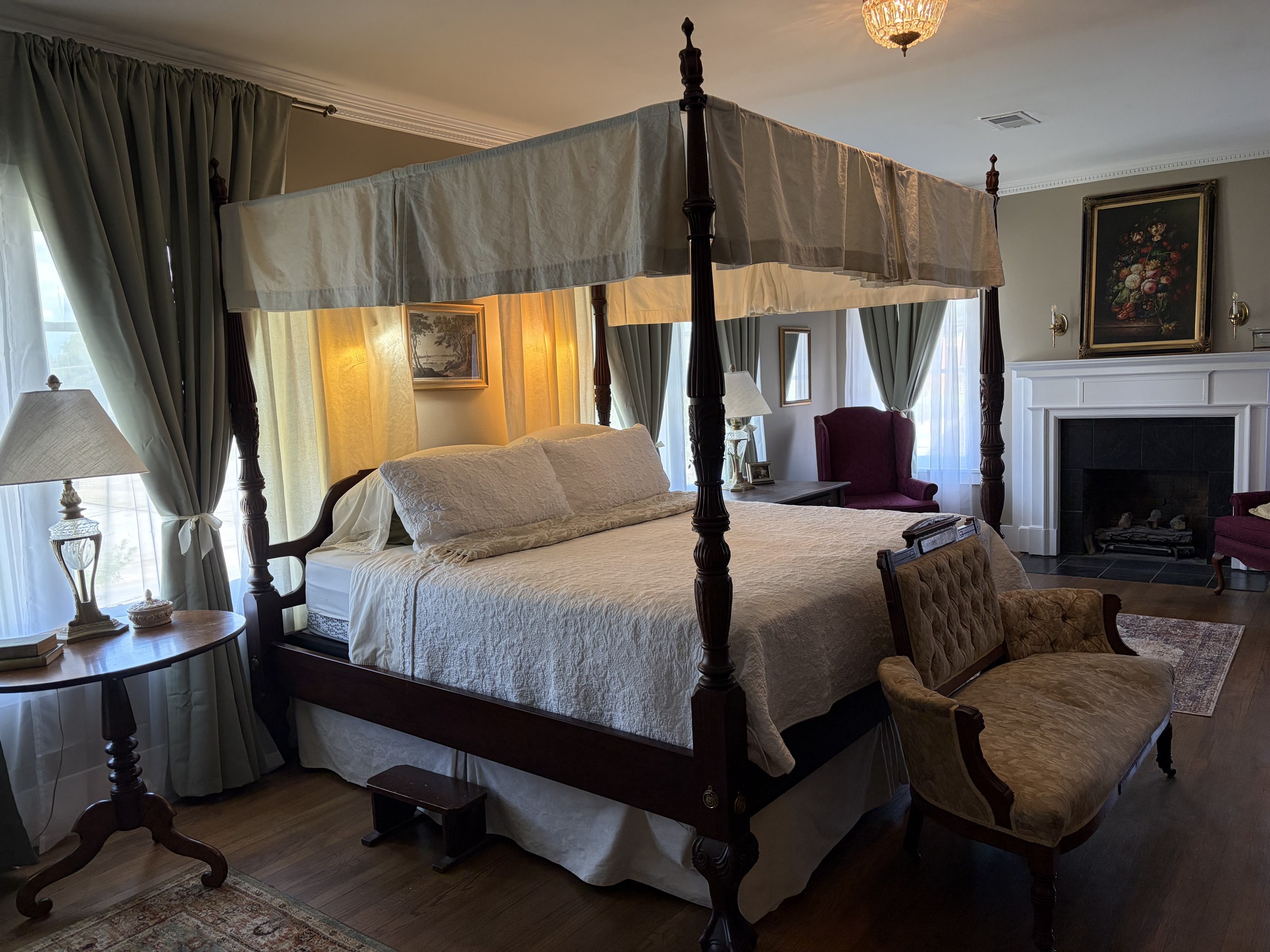 The Thompson suite: a dark wood four-poster canopy bed, fireplace, and sage drapes.